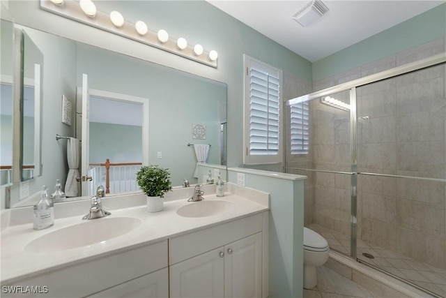 bathroom featuring a shower with door, vanity, tile patterned flooring, and toilet