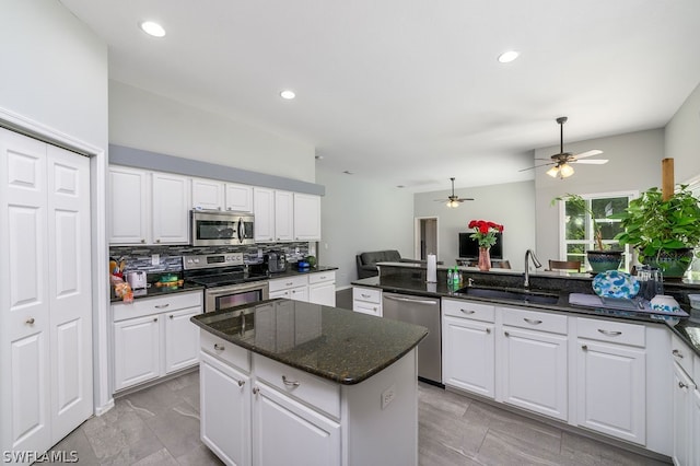 kitchen with appliances with stainless steel finishes, white cabinetry, ceiling fan, and a kitchen island