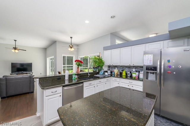 kitchen with dark stone counters, hardwood / wood-style flooring, ceiling fan, stainless steel appliances, and white cabinets