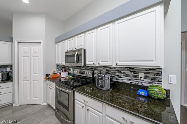 kitchen with dark stone counters, white cabinetry, decorative backsplash, and stainless steel appliances