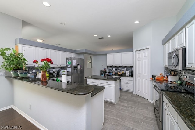 kitchen featuring dark stone counters, white cabinetry, tasteful backsplash, appliances with stainless steel finishes, and kitchen peninsula