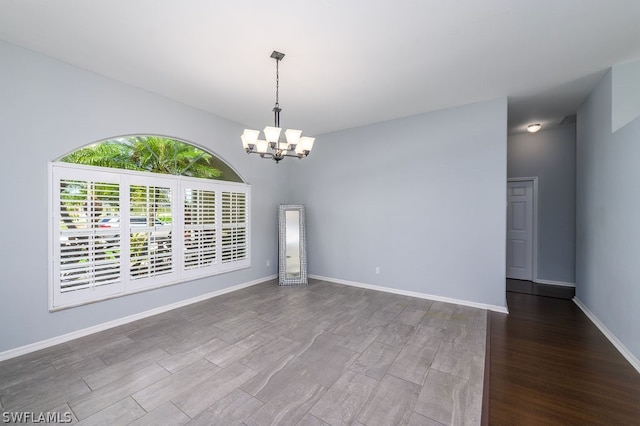 unfurnished room with an inviting chandelier and hardwood / wood-style flooring