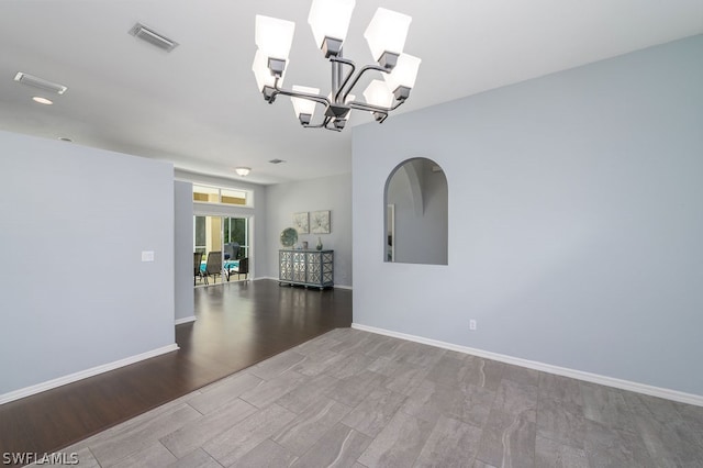 spare room with hardwood / wood-style flooring and an inviting chandelier