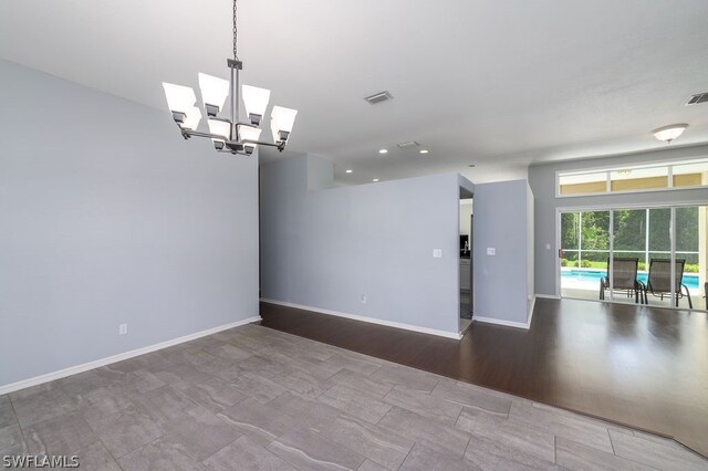 unfurnished room with wood-type flooring and a notable chandelier