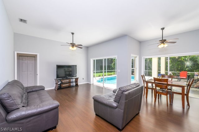 living room featuring a healthy amount of sunlight, ceiling fan, and dark wood-type flooring