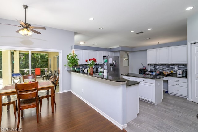 kitchen with stainless steel fridge, white cabinetry, and tasteful backsplash