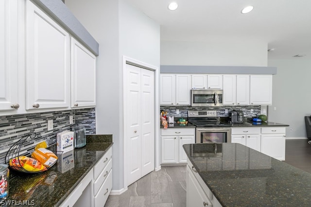 kitchen with dark stone countertops, appliances with stainless steel finishes, backsplash, and white cabinetry