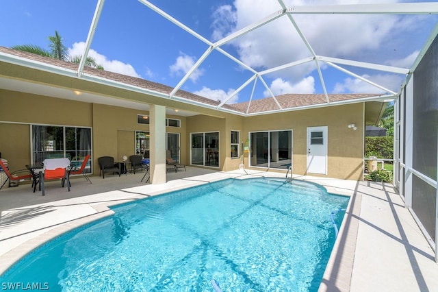 view of swimming pool featuring glass enclosure and a patio area