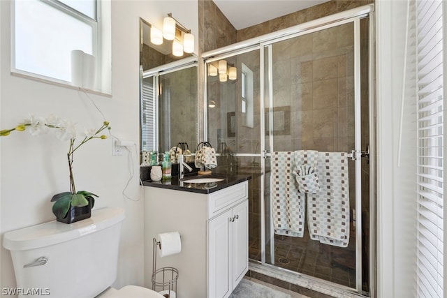 bathroom featuring a shower with door, vanity, and toilet