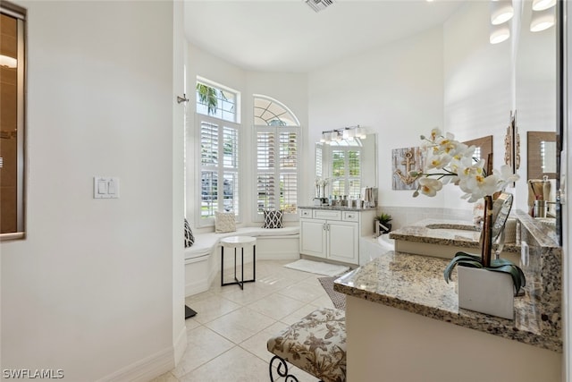 bathroom featuring a bath, tile patterned flooring, a wealth of natural light, and vanity