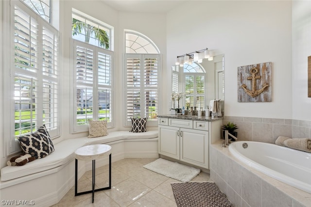 bathroom with tile patterned flooring, tiled bath, and vanity