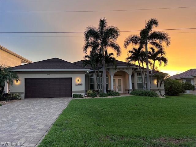 view of front of home with a garage and a lawn