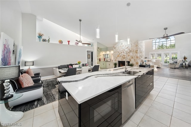 kitchen featuring a stone fireplace, ceiling fan, and a kitchen island with sink