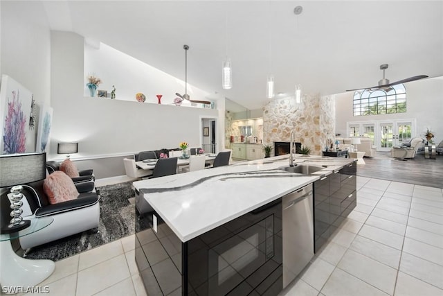 kitchen featuring stainless steel dishwasher, a kitchen island with sink, hanging light fixtures, and light tile patterned floors