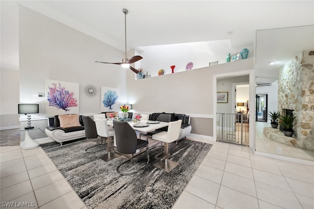 tiled dining room featuring a fireplace, high vaulted ceiling, and ceiling fan