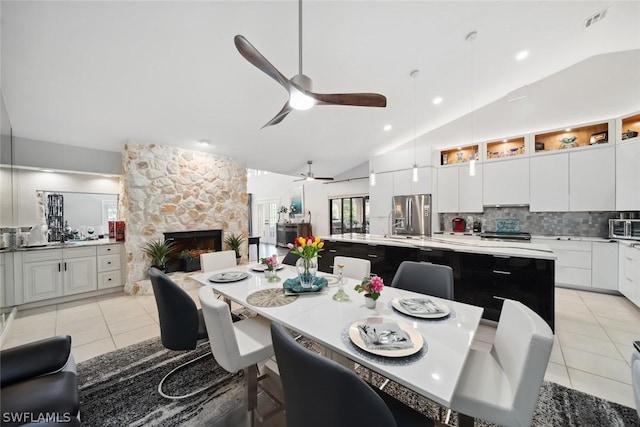 tiled dining space with a fireplace, high vaulted ceiling, and ceiling fan