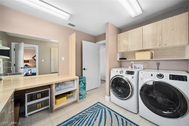 laundry area featuring cabinets, sink, light tile patterned flooring, and washing machine and dryer