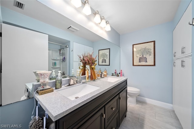 bathroom featuring tile patterned flooring, a tile shower, toilet, and double sink vanity