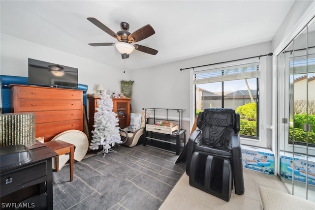 sitting room with dark tile patterned floors and ceiling fan