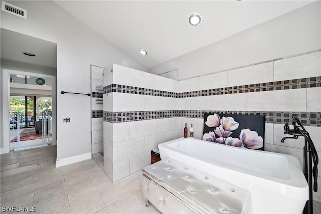 bathroom with separate shower and tub, vaulted ceiling, and tile walls