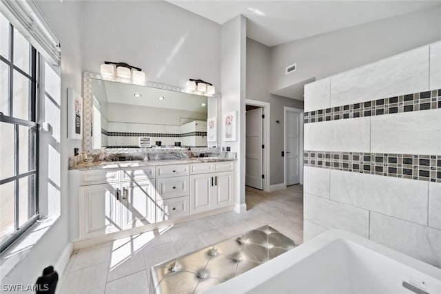 bathroom featuring a tub to relax in, tile patterned floors, vanity, and lofted ceiling