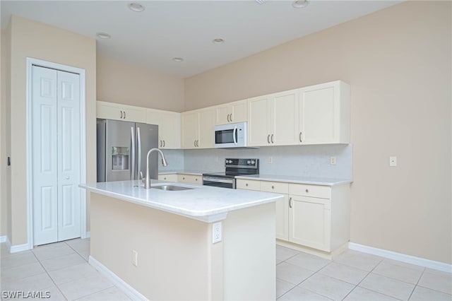 kitchen with appliances with stainless steel finishes, white cabinets, decorative backsplash, and a kitchen island with sink