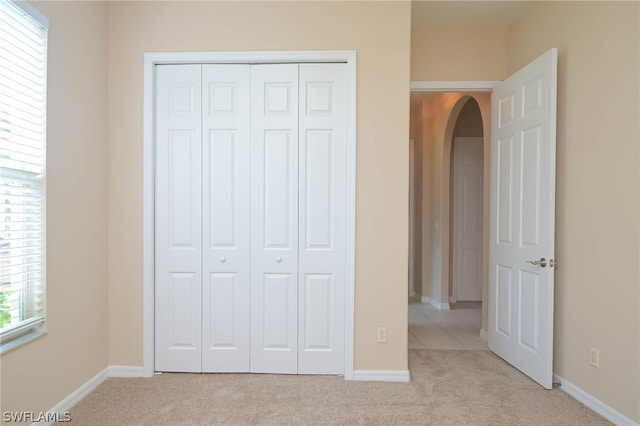 unfurnished bedroom with a closet and light colored carpet