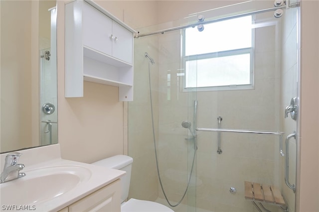 bathroom with a shower with shower door, toilet, and vanity