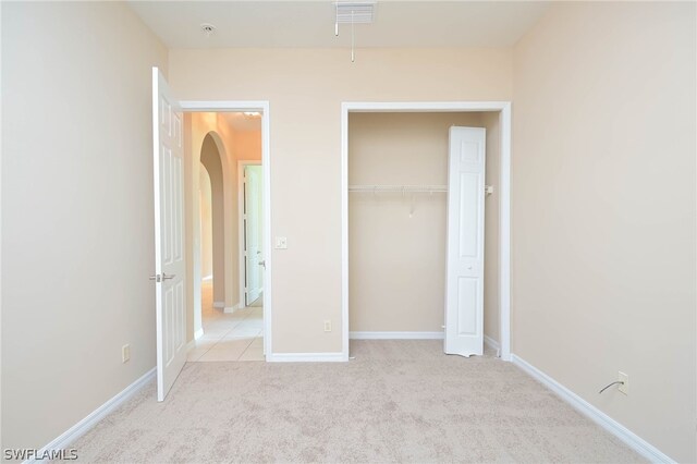 unfurnished bedroom with light colored carpet and a closet