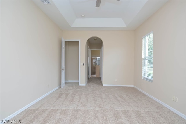 unfurnished room with light colored carpet and a raised ceiling