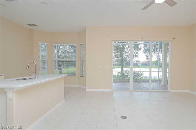 tiled spare room featuring sink, a wealth of natural light, and ceiling fan