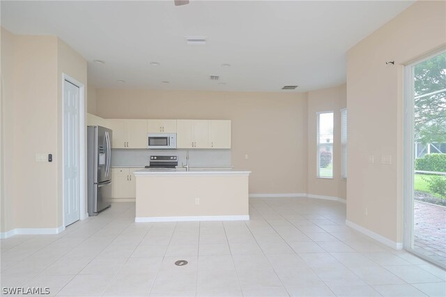 kitchen with range, white cabinets, light tile patterned floors, a kitchen island with sink, and stainless steel refrigerator with ice dispenser