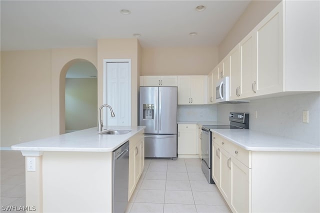 kitchen with white cabinetry, light tile patterned floors, appliances with stainless steel finishes, sink, and a center island with sink