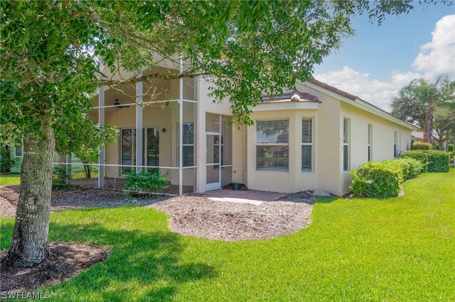 back of house with ceiling fan and a lawn