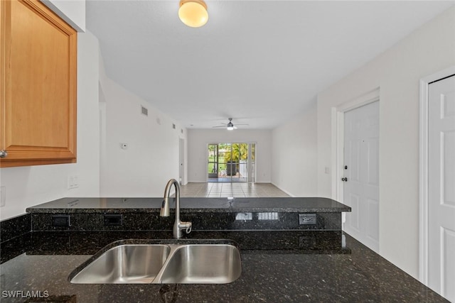 kitchen featuring sink, ceiling fan, and dark stone counters