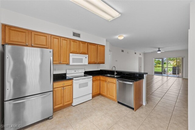 kitchen with sink, light tile patterned floors, dark stone counters, kitchen peninsula, and stainless steel appliances