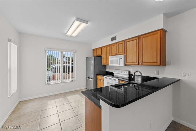 kitchen with light tile patterned flooring, sink, kitchen peninsula, white appliances, and dark stone counters