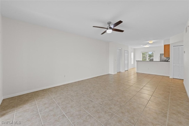 unfurnished room with light tile patterned floors, ceiling fan, and baseboards