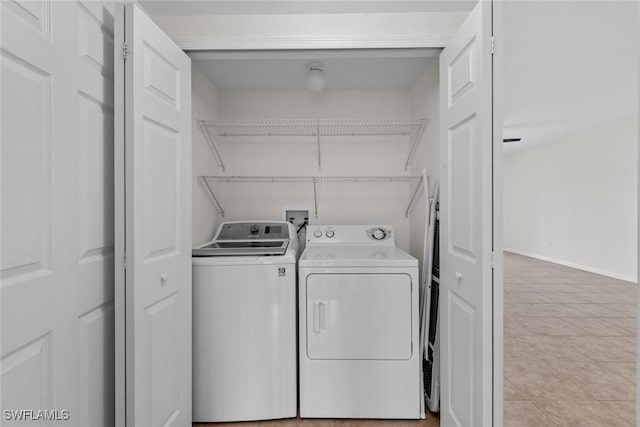 laundry area with washer and dryer, laundry area, baseboards, and light tile patterned floors