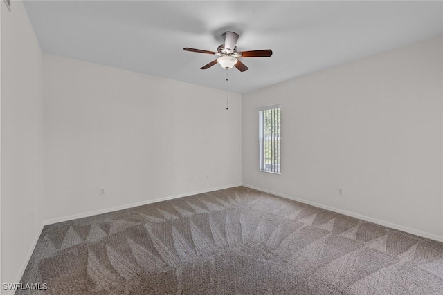 carpeted spare room with a ceiling fan and baseboards