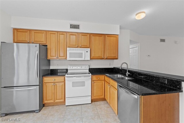 kitchen featuring sink, light tile patterned floors, appliances with stainless steel finishes, kitchen peninsula, and dark stone counters