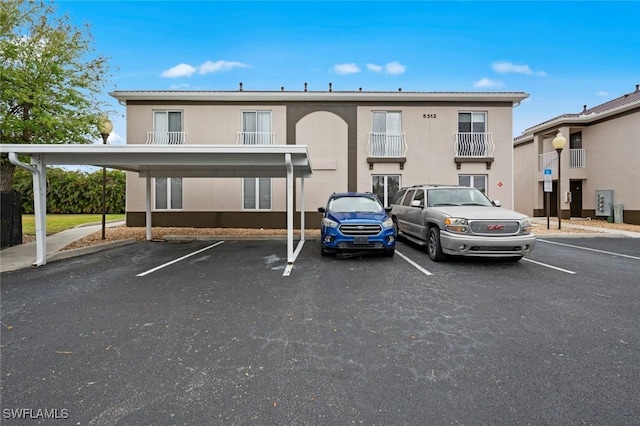 view of property featuring covered and uncovered parking