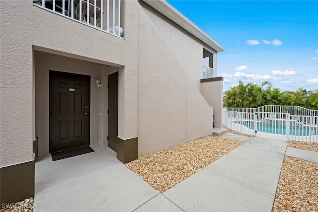 doorway to property with a patio area, fence, a fenced in pool, and stucco siding