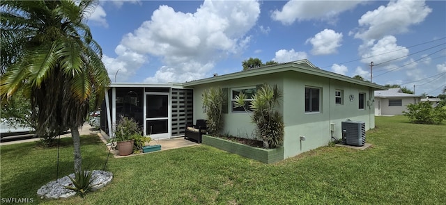 rear view of property with cooling unit and a lawn