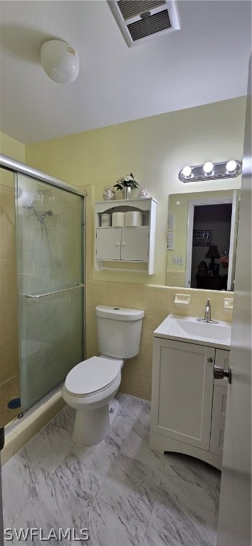 bathroom with tile patterned flooring, an enclosed shower, toilet, vanity, and tile walls