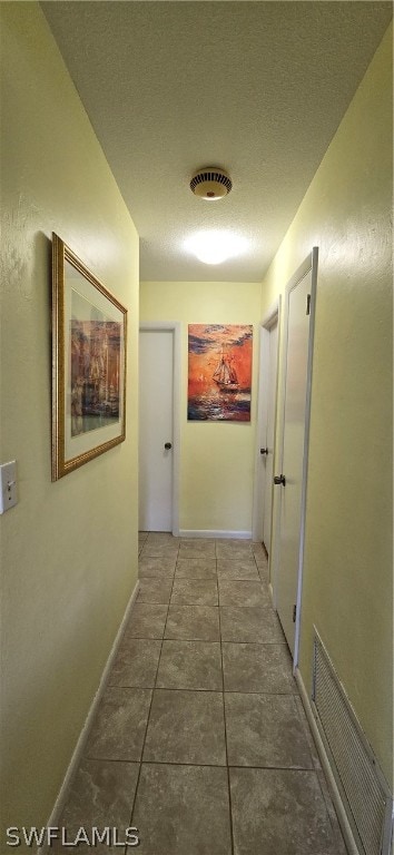 hallway with tile patterned floors and a textured ceiling