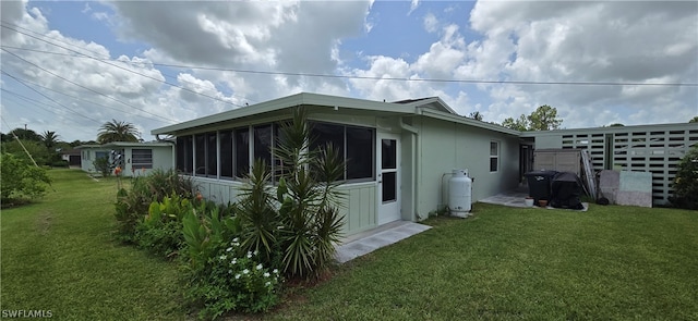 view of side of property with a sunroom and a lawn