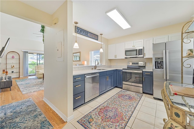 kitchen featuring sink, appliances with stainless steel finishes, light hardwood / wood-style floors, blue cabinetry, and white cabinets