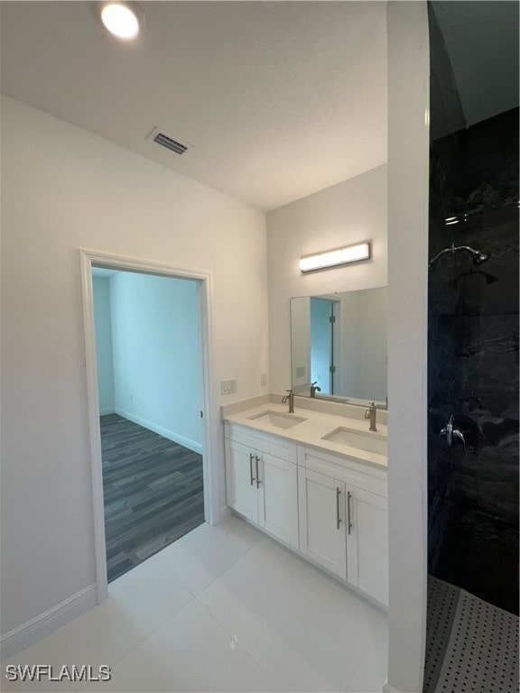 bathroom with vanity, wood-type flooring, and tiled shower