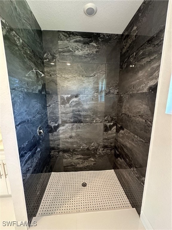 bathroom with tiled shower and a textured ceiling